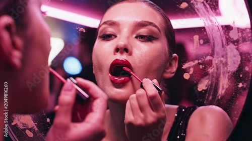  Nightclub mirror reflection of woman applying red lipstick