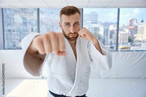Photos Martial arts focus, male athlete in gym executing punch during vigorous dojo tra