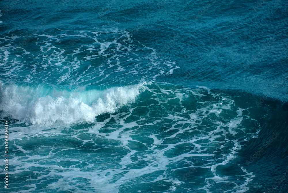 Naklejka premium Turbulent teal ocean waves with white foam