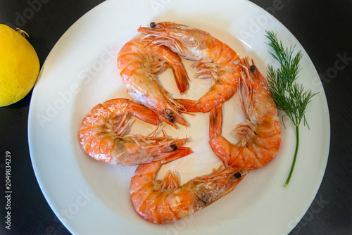 Cooked shrimp served on a white plate. Shrimp cooking in boiling water. Raw shrimp on a white plate