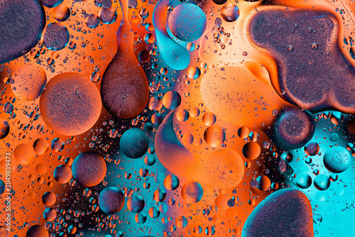 Cosmic orange oil bubbles on blue backdrop photo