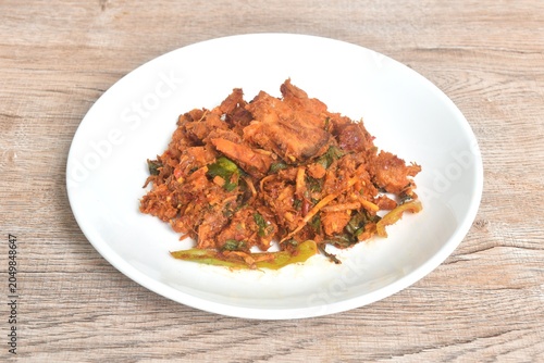 fried spicy slice stingray fish with finger root and basil leaf in curry sauce on plate