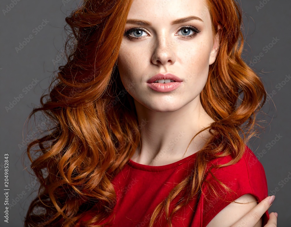 Fototapeta premium Portrait of a young woman with curly red hair and red scarf.