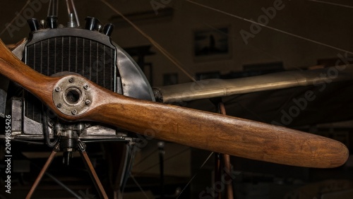 The wooden propeller of a vintage monoplane in a quiet hangar.