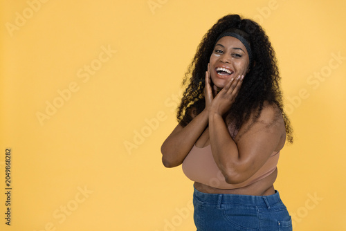 Fotografija Woman touching cheeks and laughing, initiating animated marketing on yellow back