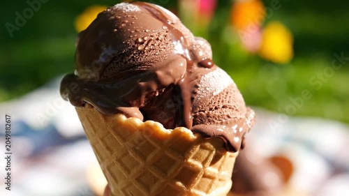 Close up of a chocolate ice cream cone with two scoops on a sunny day