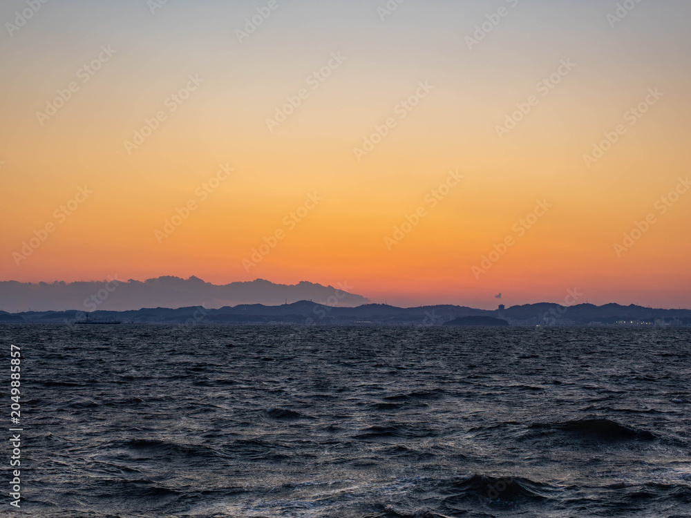 Fototapeta premium 黄金色に染まる夕焼け空と波立つ冬の海