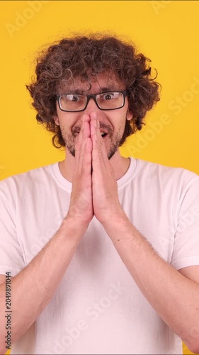 Person pressing hands together in a joyful celebratory gesture, expressing delight, triumph and an uplifting victory mood against a bright yellow background.