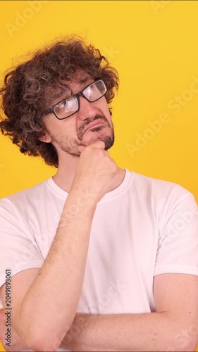 Person touching the chin and looking slightly upward in a thoughtful pose, creating a calm reflective mood against a bright yellow background.