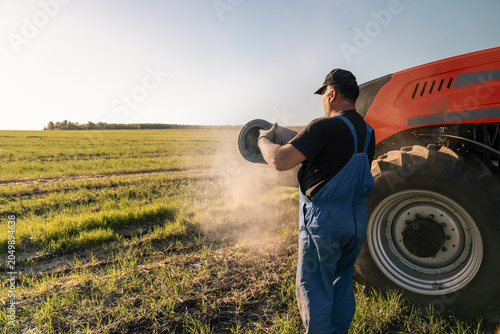 Farmer cleaning dusty tractor air filter in field, farm machinery maintenance during field work and equipment preparation for continued operation