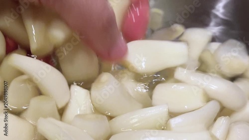 白い宝石と呼ばれるらっきょう。食用。たっぷりの水に入れたらっきょうを手で洗っているクローズアップ動画