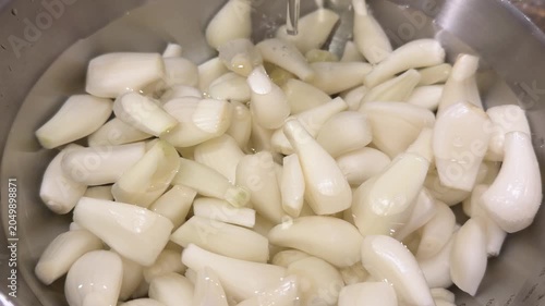 白い宝石と呼ばれるらっきょう。食用。らっきょうを洗うためにボウルに水を注いでるクローズアップ動画。