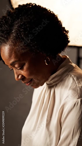 Contemplative woman with curly hair in soft natural light looking down