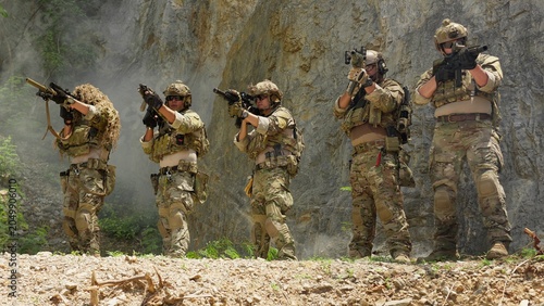 Foto A tactical special forces squad aims their rifles in formation, conducting a coordinated patrol through smoke during a military combat mission in a rocky canyon