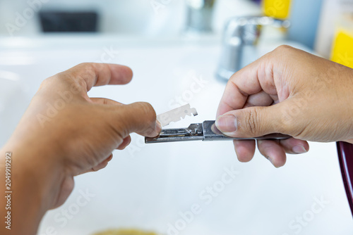Tableau sur toile Close-up of barber hands carefully inserting a new sharp blade into a straight razor