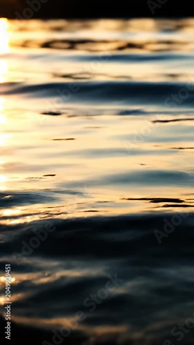 Golden sunset light reflecting on calm ocean water ripples.