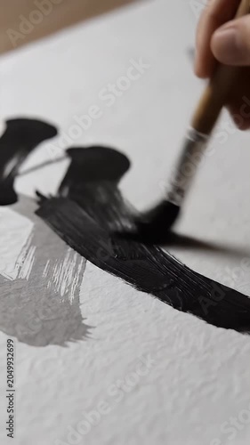 Hand painting black ink brush stroke on white paper.