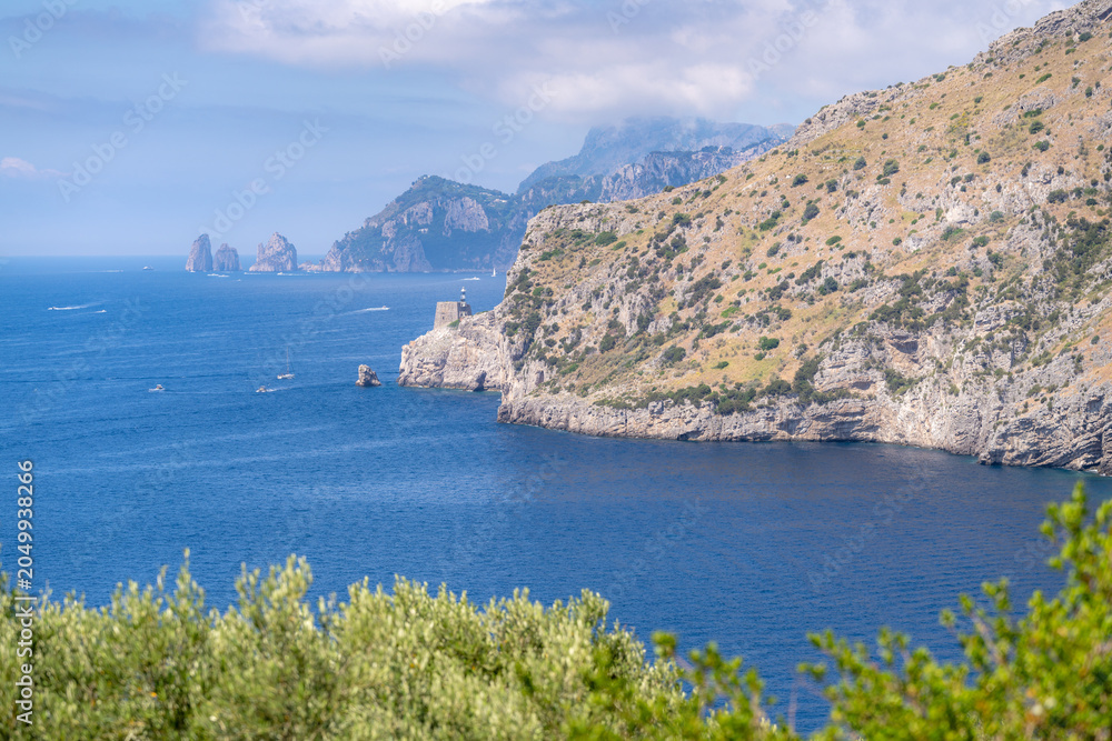 Fototapeta premium Stunning view of Ieranto Bay featuring distant Faraglioni rock formations near the island of Capri.