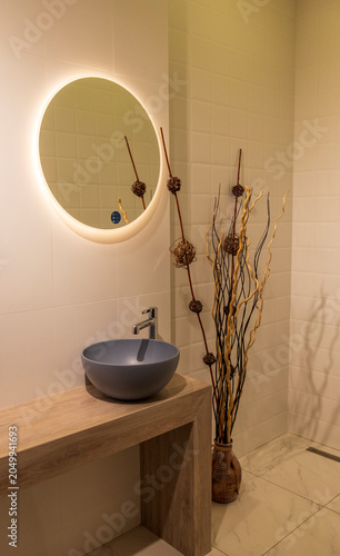 Contemporary Washroom Design Featuring Circular Backlit Mirror and Wooden Console. Interior