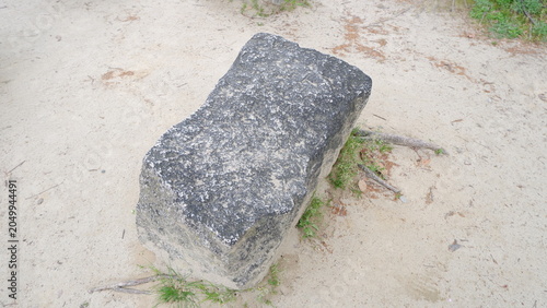 Large stone blocks resting on sandy ground in outdoor setting. Natural rock formations, textured stone surfaces, landscape design elements, minimalist nature scene, and outdoor photography concept.
