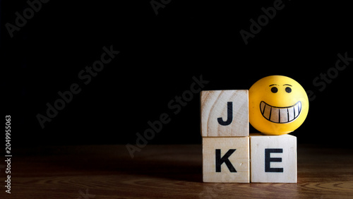 Canvas Print wooden toy blocks and smilley rubber toys arranged to spell the word JOKE & FUNNY  on a wooden surface against a dark, black background