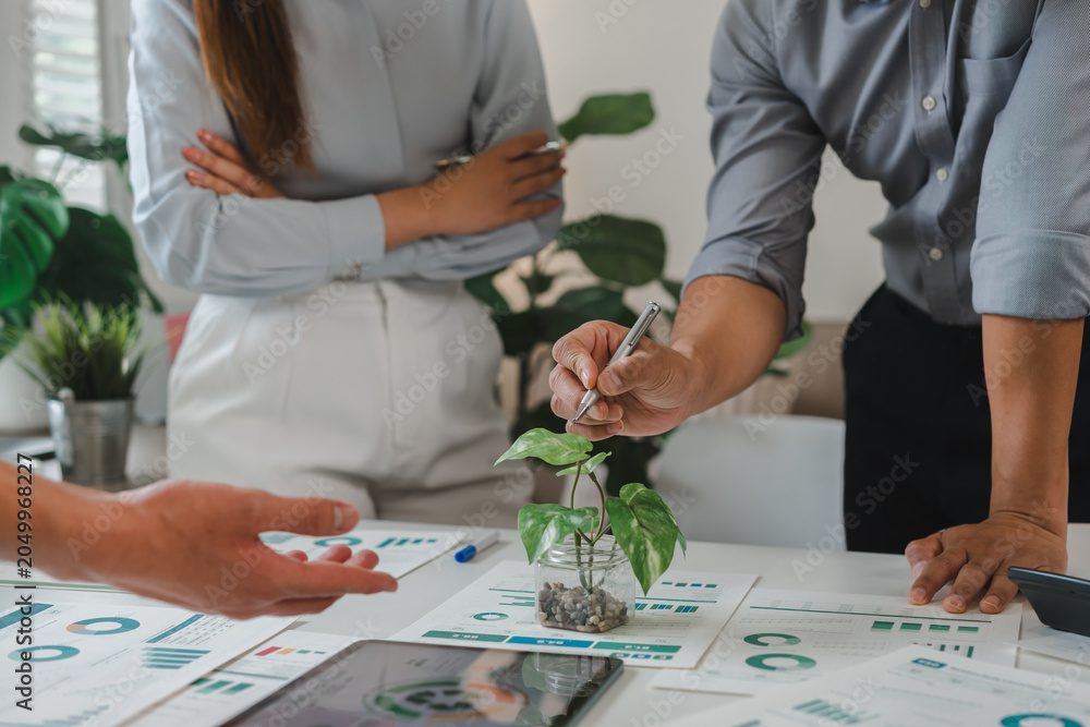 Fototapeta premium Business team discussing environmental sustainability data using plant growth charts in a modern office meeting