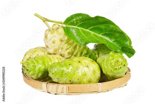 Fresh tropical noni fruits with green leaves arranged in bamboo basket isolated on white background for natural wellness
