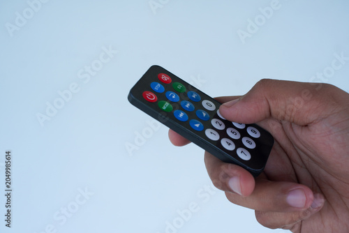 Infrared remote control with colorful buttons being pressed by a human hand, suitable for technology or entertainment concepts.