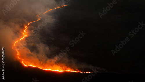 Quadro su tela Aerial view of an active wildfire spreading across a dark landscape with glowing fire lines dense smoke and visible environmental impact during a forest fire
