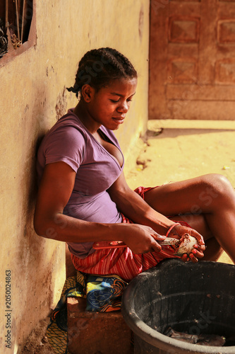 Young Cameroonian woman cleaning and preparing fresh fish in front of her home in a rural village near the Atlantic coast of Cameroon.