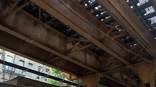 Close up of Chicago elevated train tracks showing steel beams, rivets, and structural framework. Urban infrastructure detail highlighting engineering and construction elements in daylight.