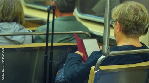 Passenger reading a book while sitting inside a Chicago subway during a commute. Calm urban transportation scene showing subway interior and everyday travel routine.