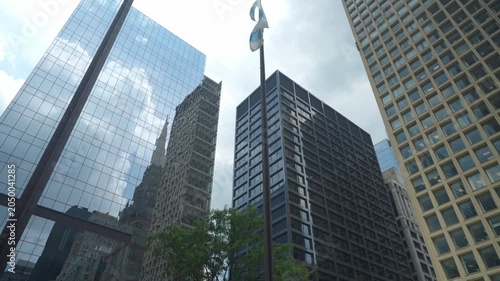 Tall skyscrapers and a historic Gothic-style tower rise above the city streets in downtown Chicago. The low angle view emphasizes architecture, height, and urban development in a modern business