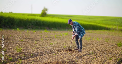 Farmer hoeing dry soil in a rural field