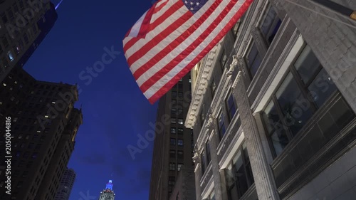 American flag hanging on a historic building facade in Chicago downtown with illuminated architecture at night. Iconic city landmark scene with classic details and urban skyline in the background.