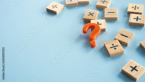 Konstfotografi An orange question mark symbol placed amidst scattered wooden tiles with mathematical operator signs, concept of problem solving, confusion, and math questions