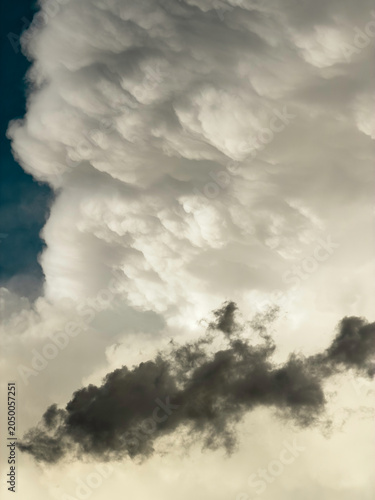 Canvas Print A dark, ragged cloudlet drifts in front of a cumulonimbus cloud with pouch-like formations that reflect sunlight at golden hour on a May evening in southwest Florida