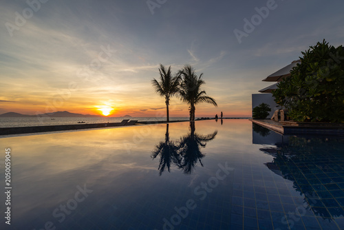 Tableau sur toile Peaceful morning view by the infinity pool with palm trees reflecting in the wat