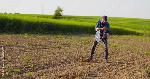 Farmer tending a cultivated field with hand tool