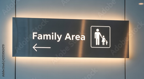 Modern illuminated indoor directional sign for Family Area with family iconography and arrow on a brushed metal panel