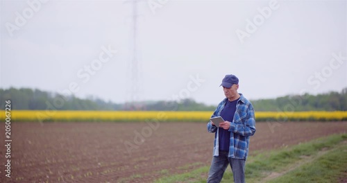 Man Checking Tablet in Agricultural Field