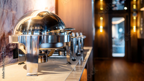 Closed round chafing dish or buffet warmer in dining area of luxury hotel. Kitchenware for keeping meals warm and fresh. Breakfast, lunch or dinner ready to serve