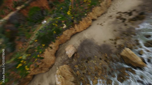 Exploring coastal cliffs and rocky beach with FPV drone along scenic ocean waves