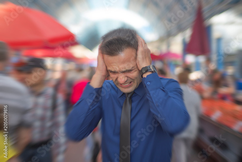 фотографія Stressed businessman suffering from panic attack or migraine on crowded city str