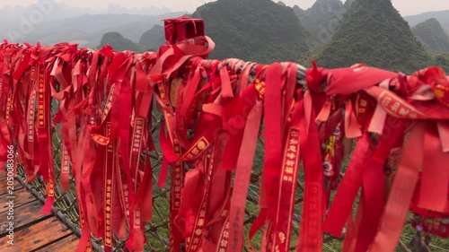 Slow motion close up of traditional red prayer ribbons on Ruyi Peak suspension bridge in Yangshuo, Guilin, China
