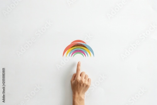 A hand pointing to a colorful rainbow arc on a white background with vibrant colors.