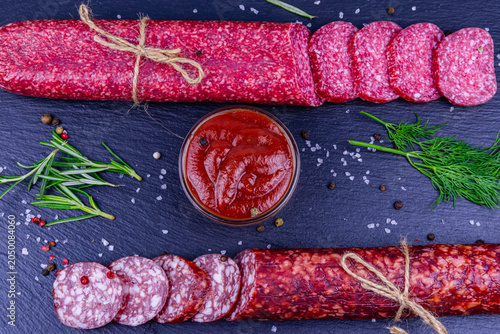 Sliced dry smoked salami sausage on a slate board. Top view
