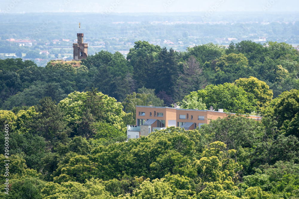 Obraz premium Residential Building and Historic Tower Surrounded by Lush Forest Landscape With Panoramic View