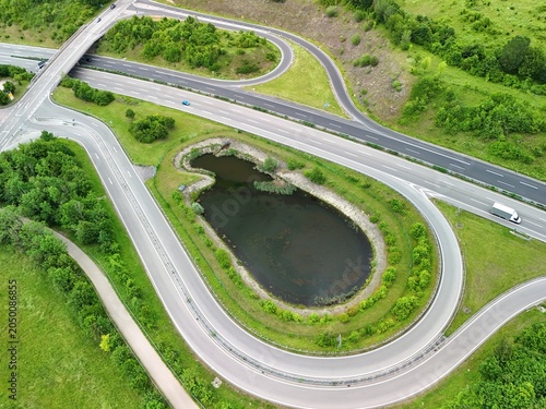 Aerial View of Highway Interchange with Curved Roads and Pond in Green Landscape
