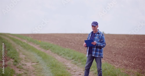 Farmer standing in a rural field with clipboard